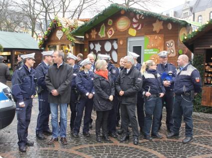Polizeipräsidentin Ursula Brohl-Sowa und Oberbürgermeister Ashok Sridharan mit den Polizeibeamtinnen und -beamten und den Angehörigen des Stadtordnungsdienstes beim Pressetermin auf dem Weihnachtsmarkt.